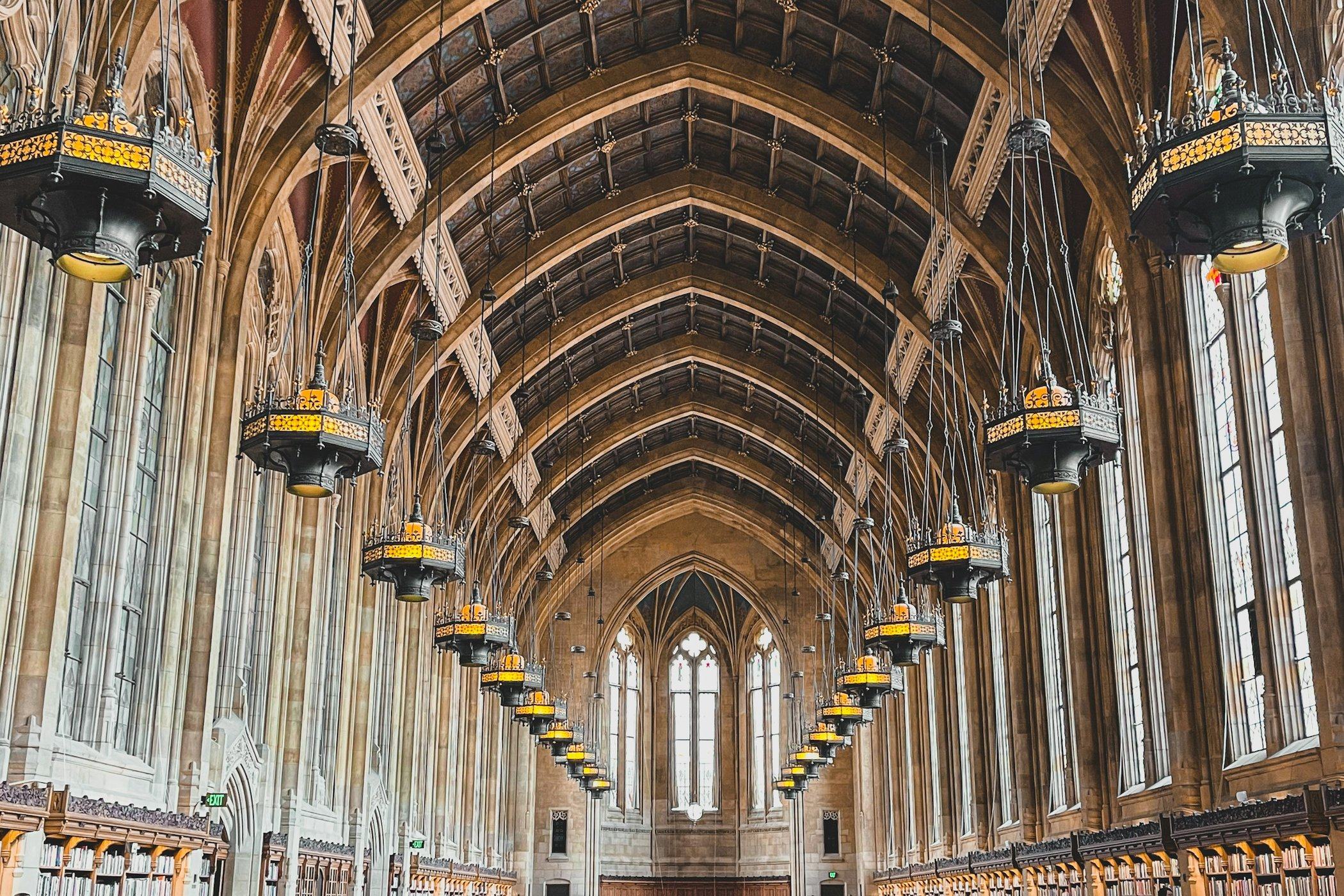 A grand university library reading room with a vaulted ceiling and long wooden tables