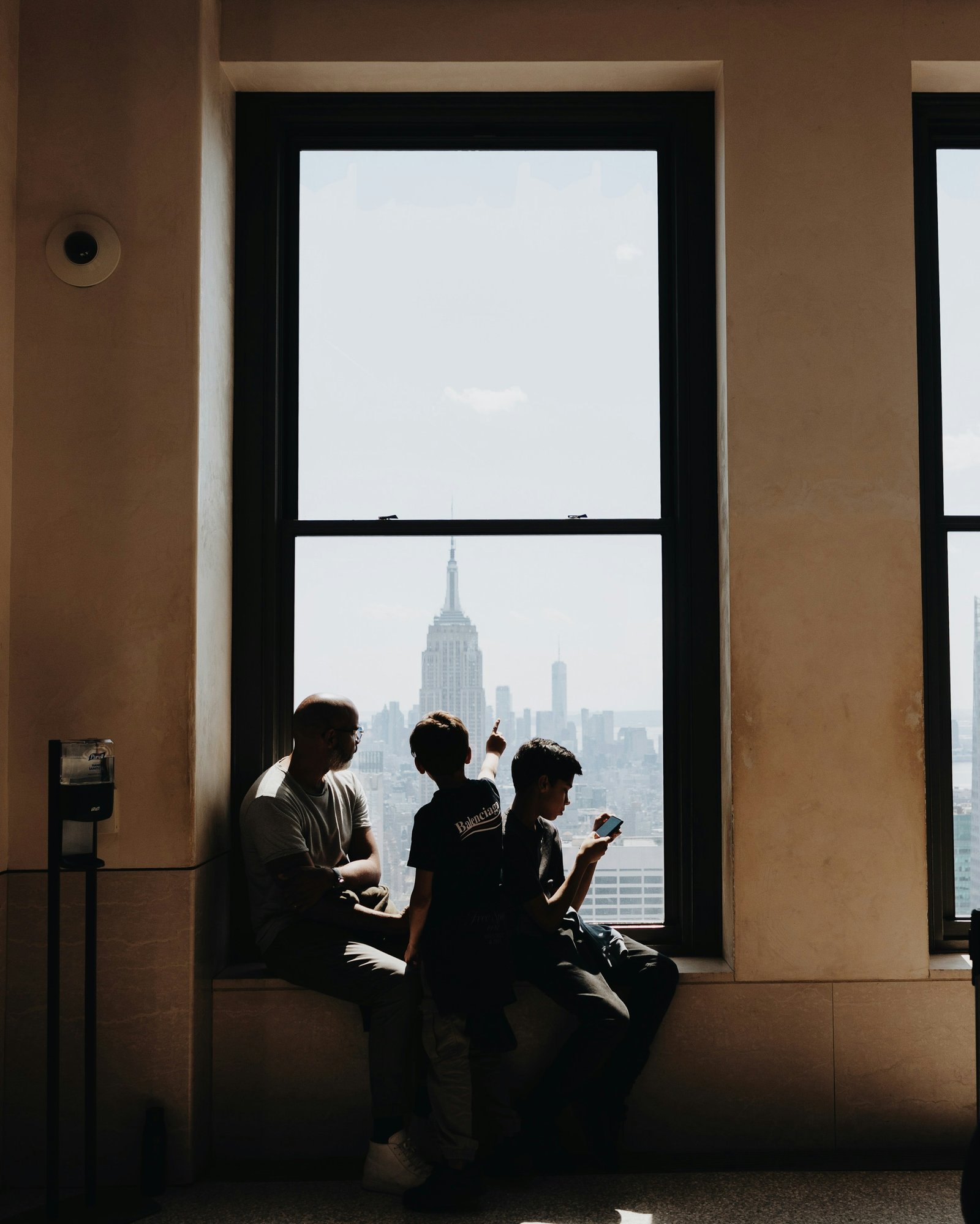 A family sitting at a window looking out over the Manhattan skyline